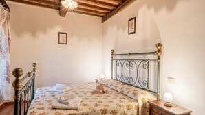 Un dormitorio con cama, mesita de noche, lámpara y ventilador de techo.