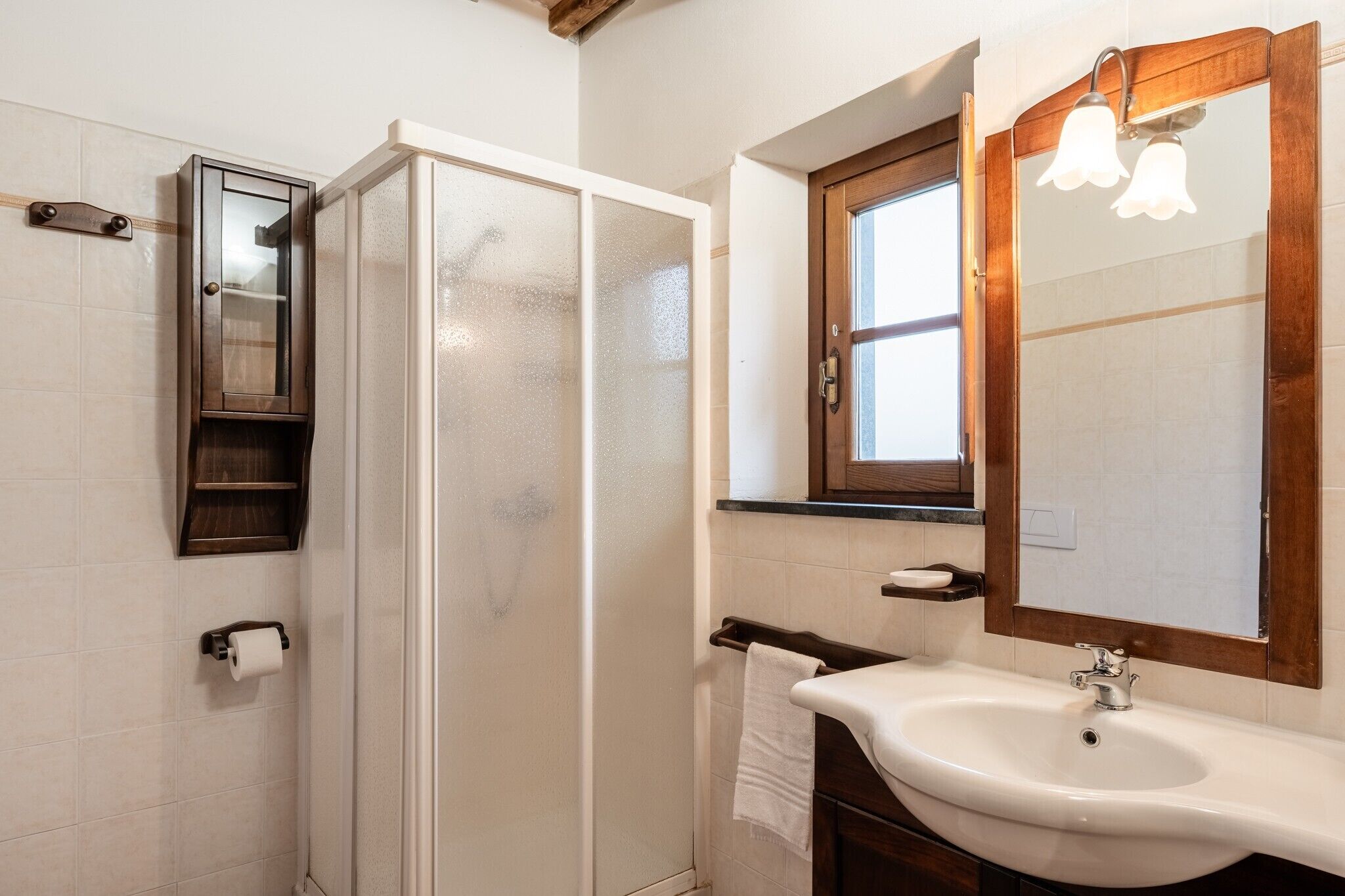 A bathroom with a shower, a sink, a mirror, and a towel rack.