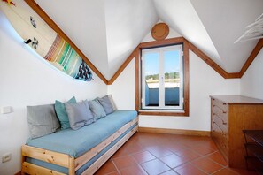 A small, cozy room with a wooden bed, a window, and a dresser.
