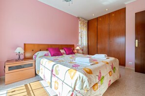 Une chambre à coucher comprenant un lit, une table de chevet, une armoire en bois et une fenêtre avec des rideaux.
