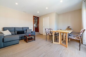 Un salon comprenant un canapé, une table basse, une table à manger avec des chaises et une porte.