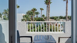 A balcony with a white railing, a glass table, and two chairs.