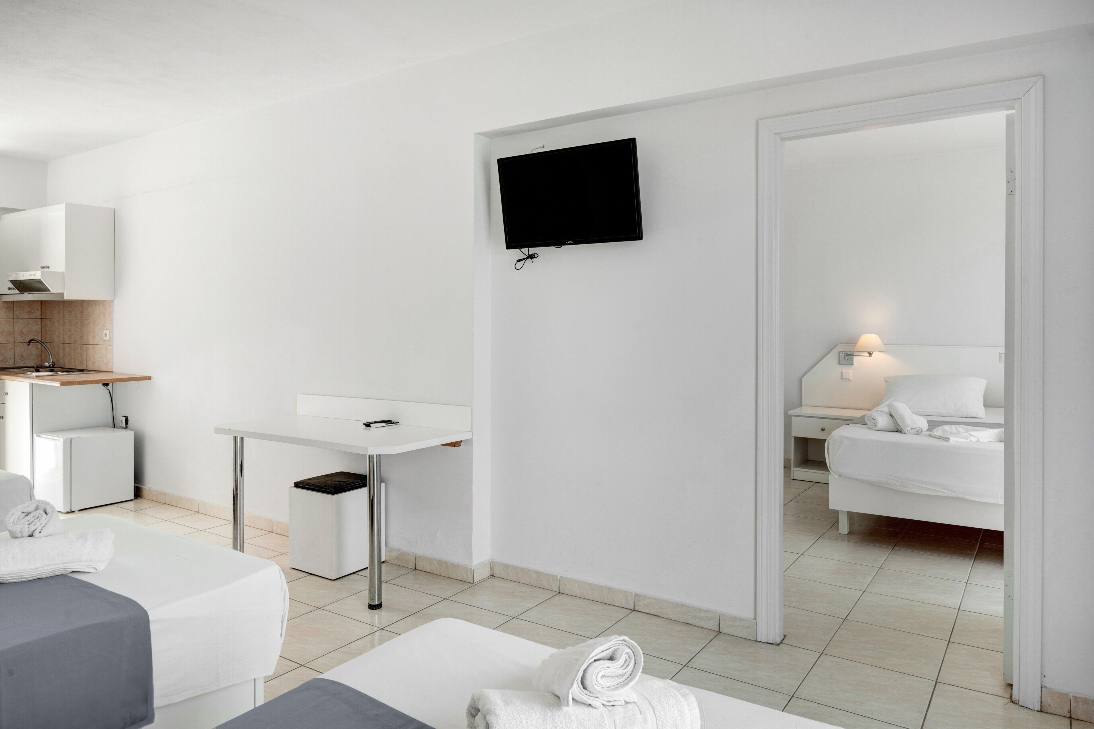 Una moderna camera d'albergo con un letto, una scrivania, una televisione e uno specchio.