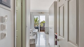A hotel corridor with a sliding glass door leading to a balcony with a view of palm trees. - Studio Apartment 'Evripides Triple Room 2' with Shared Pool, Shared Garden and Air Conditioning (Kardamaina)