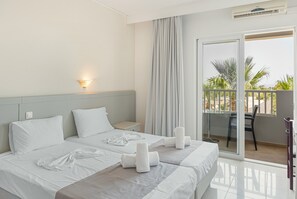 Une chambre d’hôtel avec deux lits, un balcon offrant une vue, un bureau et une chaise.