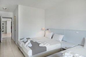 Quarto de hotel com cama, mesa de cabeceira e abajur.