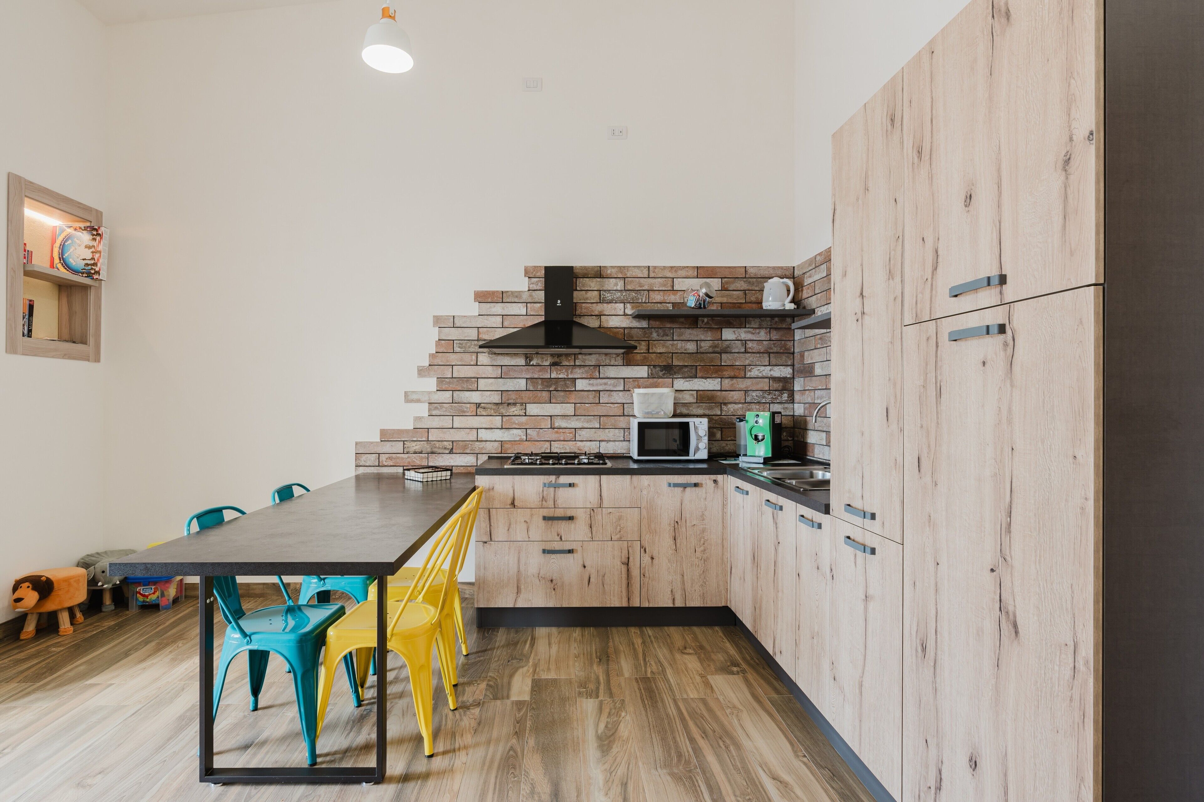 A modern kitchen with wooden cabinets, a brick backsplash, and a dining area with a table and chairs.