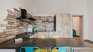 Une cuisine moderne avec un mur de fond en briques, un îlot central doté de chaises et des armoires en bois.