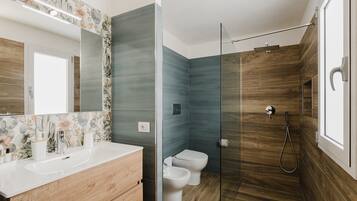Et moderne badeværelse med bruser, toilet og håndvask.