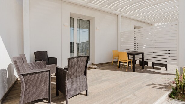 Un espace extérieur abrité, aménagé avec des meubles en osier, une table et des chaises.