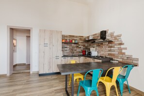 Uma cozinha moderna com painel de ladrilho, armários de madeira, bancada escura e cadeiras coloridas.