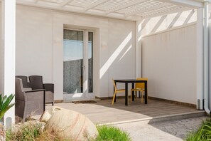 A covered patio with wicker furniture, a table, and chairs.