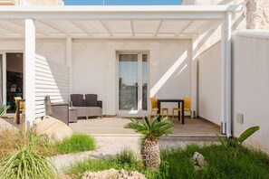 Un espacio al aire libre cubierto con mesa y sillas, una puerta y vistas a la ciudad.