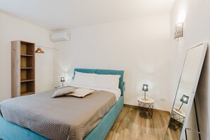 Quarto com cama, mesas de cabeceira, guarda-roupa e espelho.