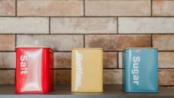 Three containers labeled 'salt,' 'coffee,' and 'sugar' on a shelf against a brick wall.