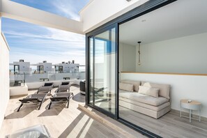 Un soggiorno moderno con parete in vetro, un divano, un tavolino e un balcone con sedie.