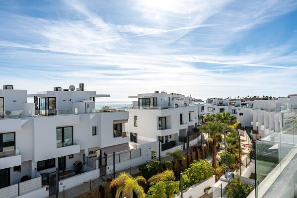 Un moderno quartiere residenziale con edifici bianchi, balconi e cielo sereno.