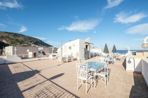 Eine Dachterrasse mit Sitzgelegenheiten im Freien, einem Pool und Blick auf das Meer.