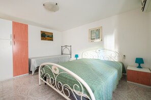 Une chambre à coucher avec un lit, une table de chevet, une armoire, un tableau et une fenêtre.