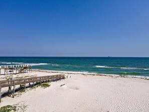 Ein Strand mit einer Holzsteganlage und blauem, klarem Himmel.