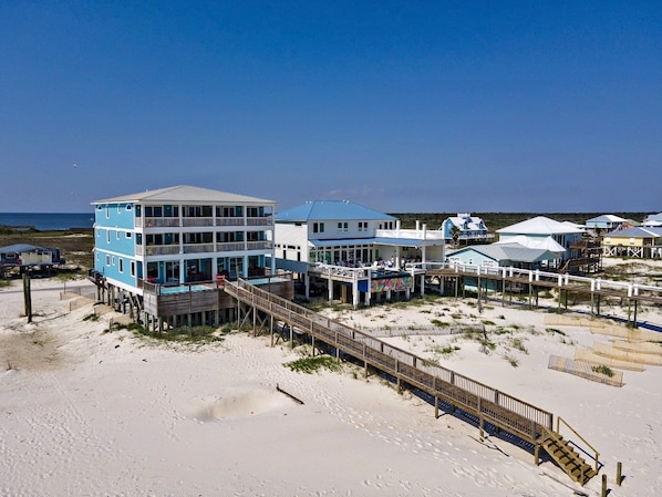 A beachfront hotel with multiple buildings, a wooden boardwalk, and a pier.