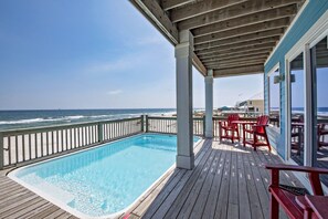 A wooden deck with a pool and red chairs overlooking the ocean. - BeachFront 9Bed EasyBreezy West (Gulf Shores)
