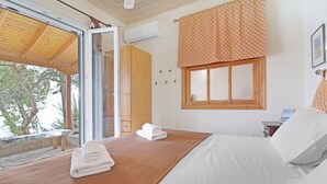 Una camera da letto con un letto, una testiera in legno, una finestra con tenda decorata e vista sugli alberi.