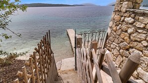 Una scala in pietra conduce a una spiaggia con acque cristalline e vista sul mare.