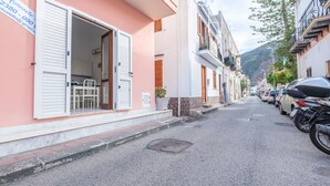 Una calle estrecha con coches estacionados y un edificio con la puerta abierta.