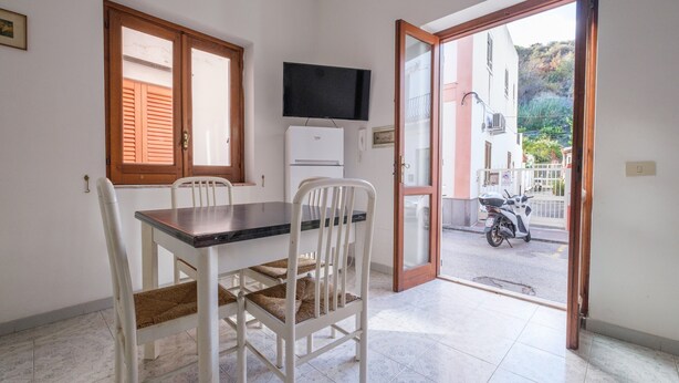 Una habitación con una mesa de comedor, sillas, un televisor y una puerta que da al exterior.