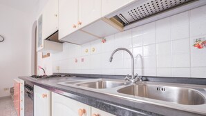 Una cocina con armarios blancos, un lavamanos doble y un grifo de acero inoxidable.