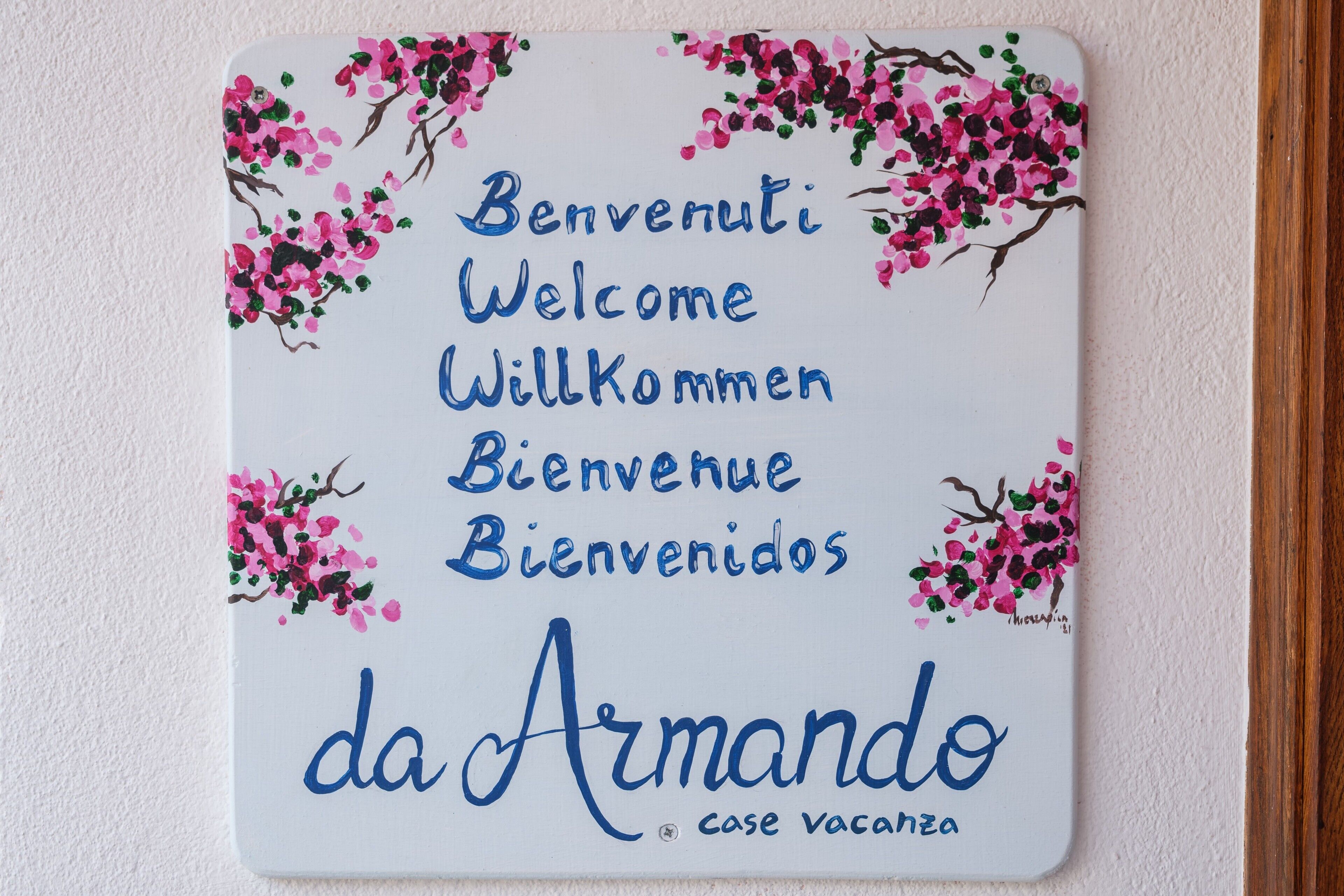 A welcome sign with multilingual greetings and the name 'da Armando' indicating a vacation rental property.