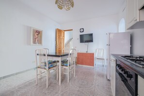 Une cuisine équipée d’une table à manger, de chaises, d’un téléviseur et d’un réfrigérateur.