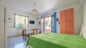 Une chambre à coucher comprenant un lit, un bureau, une chaise, une télévision et une armoire.