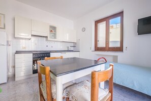 Une cuisine de taille réduite avec des meubles blancs, une cuisinière et une table à manger avec des chaises.