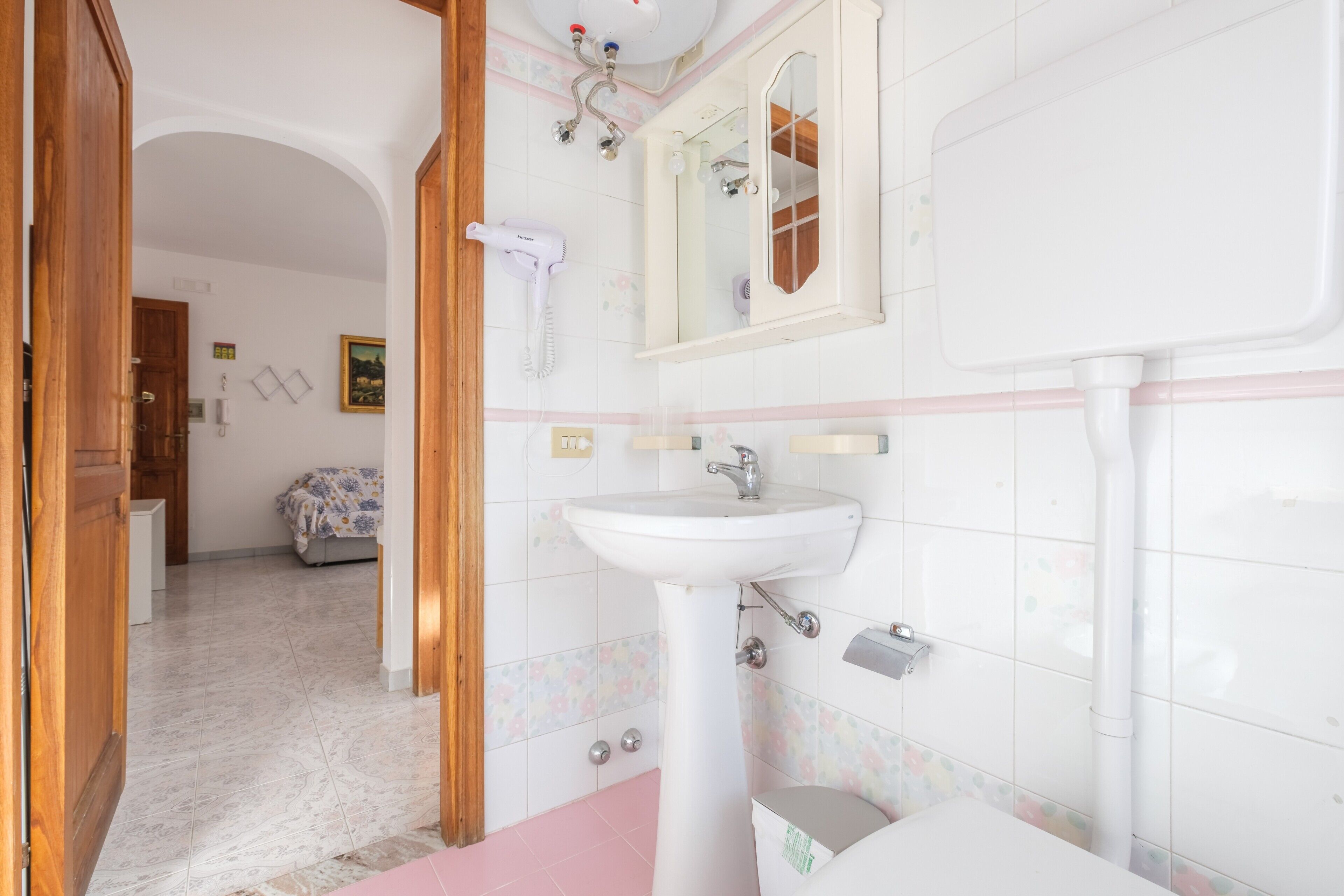A bathroom with a sink, mirror, and shower.