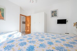 Un dormitorio con cama, armario, televisión y puerta que da a otra habitación.
