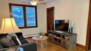 A living room with a sofa, a coffee table, a lamp, a TV, and a fireplace.