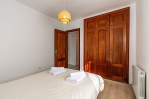 A bedroom with a bed, wooden wardrobe, and a radiator.