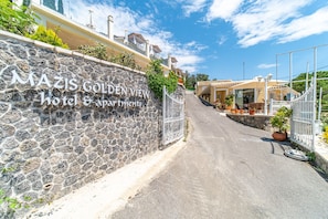 A stone wall with a sign for 'MAZIS GOLDEN VIEW hotel & apartments.'