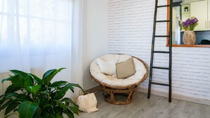 A room with a white brick wall, a wicker chair with cushions, a potted plant, and a ladder leaning against the wall. - Holiday Home 'Villa Mar' with Sea View, Private Pool and Wi-Fi (Teià)