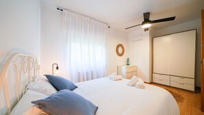 A bedroom with a bed, a ceiling fan, a bedside table, a wardrobe, and a window with curtains. - Holiday Home 'Villa Mar' with Sea View, Private Pool and Wi-Fi (Teià)