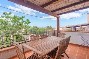 Une table et des chaises en bois sur une terrasse offrant une vue sur la verdure et les bâtiments.