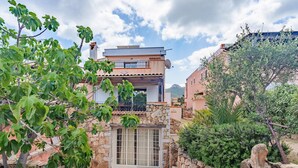 A two-story house with a stone facade, a balcony, and a view of the surrounding landscape. - Holiday Home 'Villa Alfredo Golfo Aranci' with Sea View, Private Terrace, and Air Conditioning (GolfoAranci)