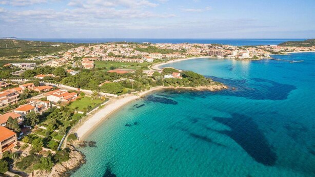 An aerial view of a coastal town with a beach, clear blue waters, and buildings with red roofs. - Holiday Home 'Villa Alfredo Golfo Aranci' with Sea View, Private Terrace, and Air Conditioning (GolfoAranci)