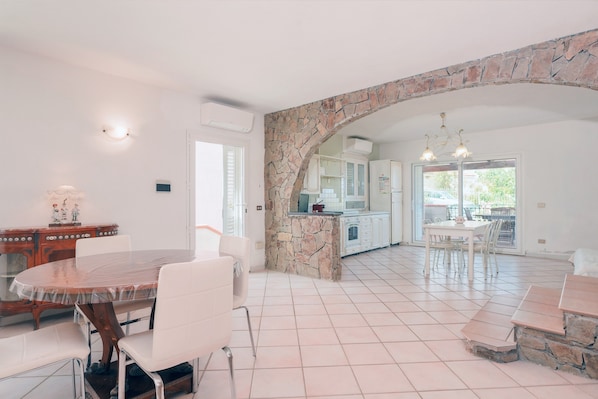 Una cocina amplia con un arco de piedra, armarios blancos y un comedor con una mesa y sillas redondas.