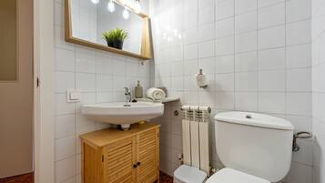 Un bagno con un lavandino bianco, un armadietto in legno, un water e uno specchio illuminato.