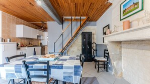 Una cocina con techo de madera, una mesa de comedor con sillas, una escalera y una chimenea.