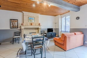 A dining area with a table set for four, a fireplace, and a sofa.