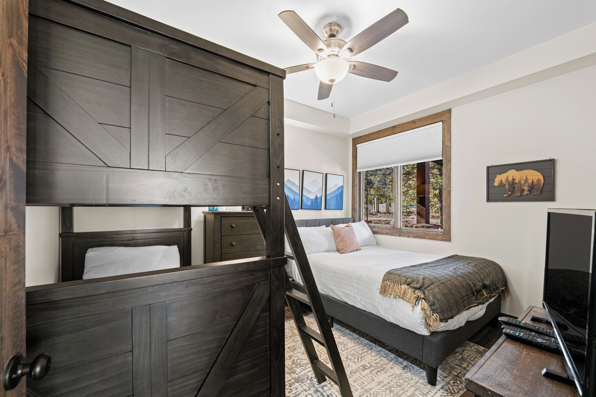 A bedroom with a bed, a ceiling fan, a TV, and a large mirror.